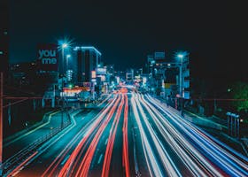 Dynamic long exposure shot of a city road at night with colorful light trails.